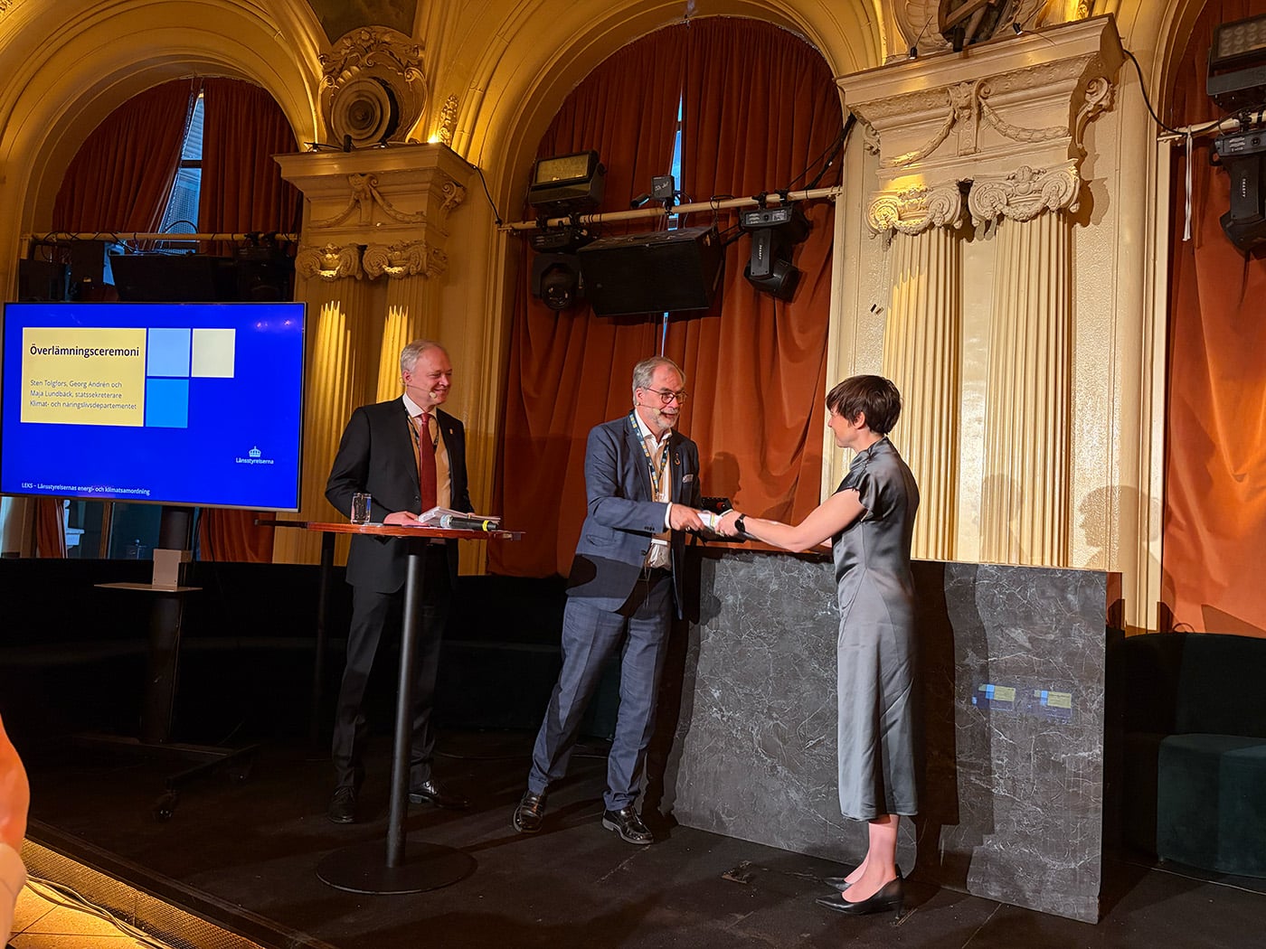 Georg Andrén lämnar över handlingsplanerna till Maja Lundbäck.