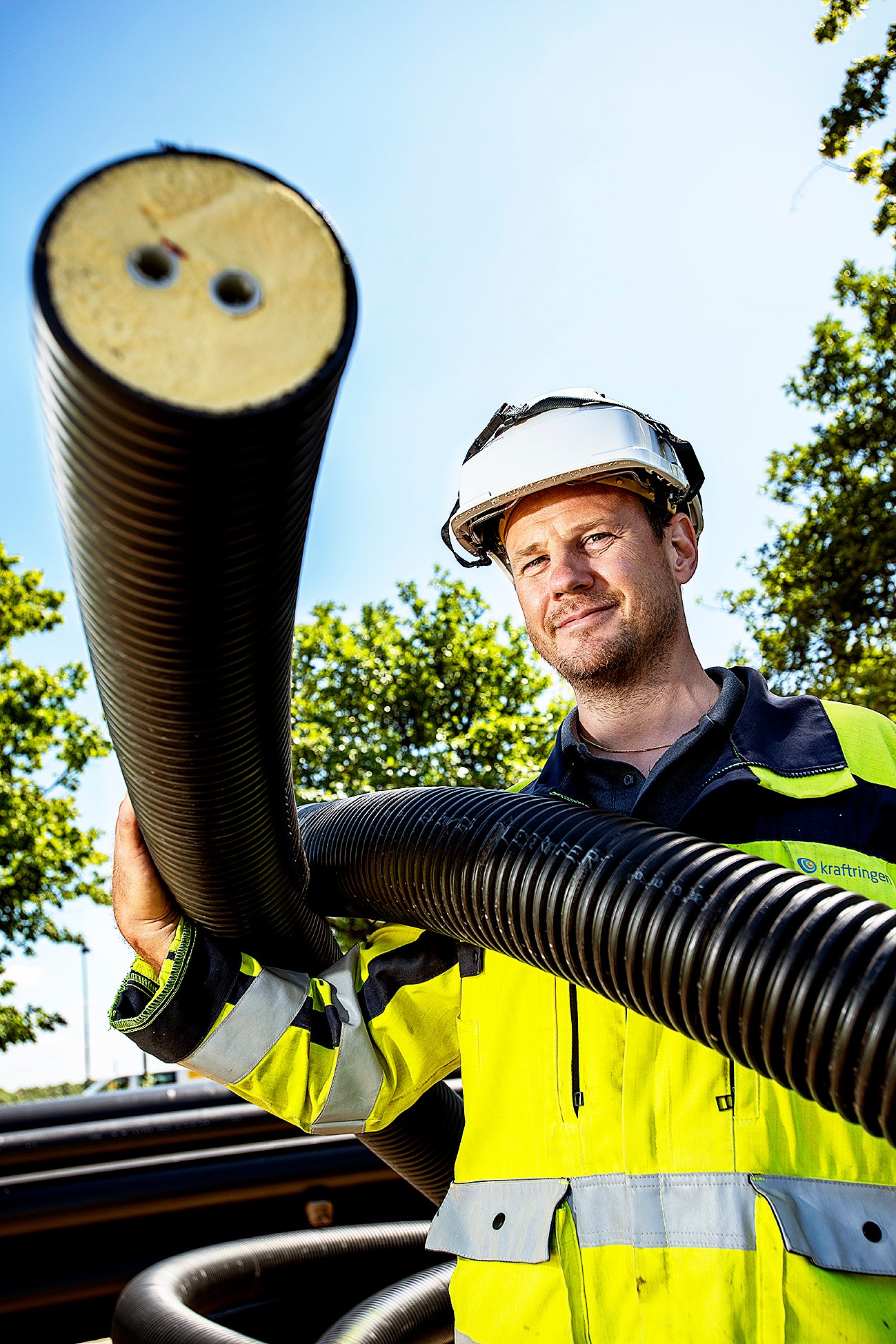 Anders Jirdén visar upp ett plaströr. I mitten syns de två mediarören för fram och returledning, med diffussionspärr mot syre och vatten. Skummet i isoleringen är nyutvecklat och har bättre isoleringsförmåga.