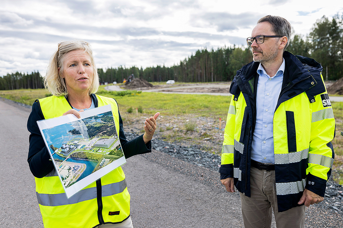 Presschefen Jenny Rees och vd Stefan Engdahl visar en skiss över hur slutförvarsområdet kommer att se ut 2035.