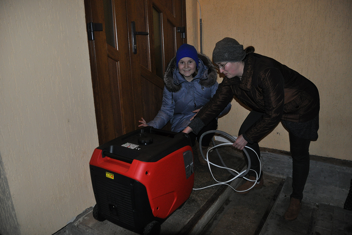 Roma och hennes dotter Daria sätter igång en bensindriven elgenerator under ett elavbrott.